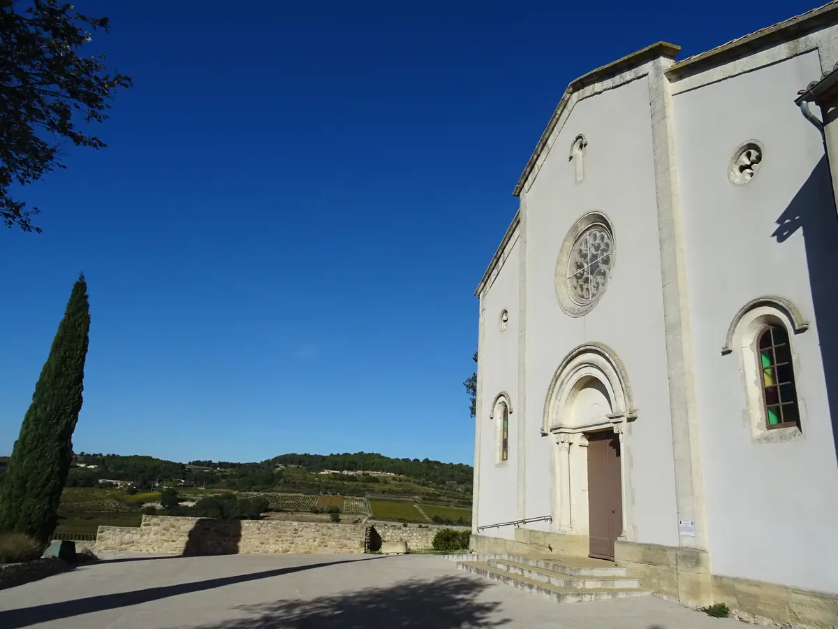 Die helle Fassade der Kirche Saint-André in Cairanne mit Portal und Rosette