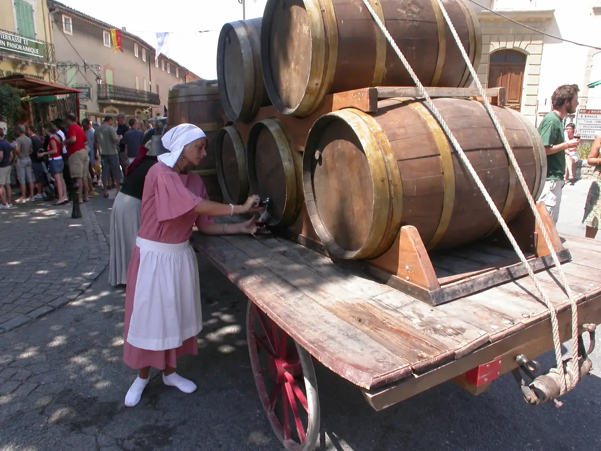 Weinverkostung neben Fässern mit kostümierten Teilnehmern beim Véraison-Fest 2006 in Châteauneuf-du-Pape