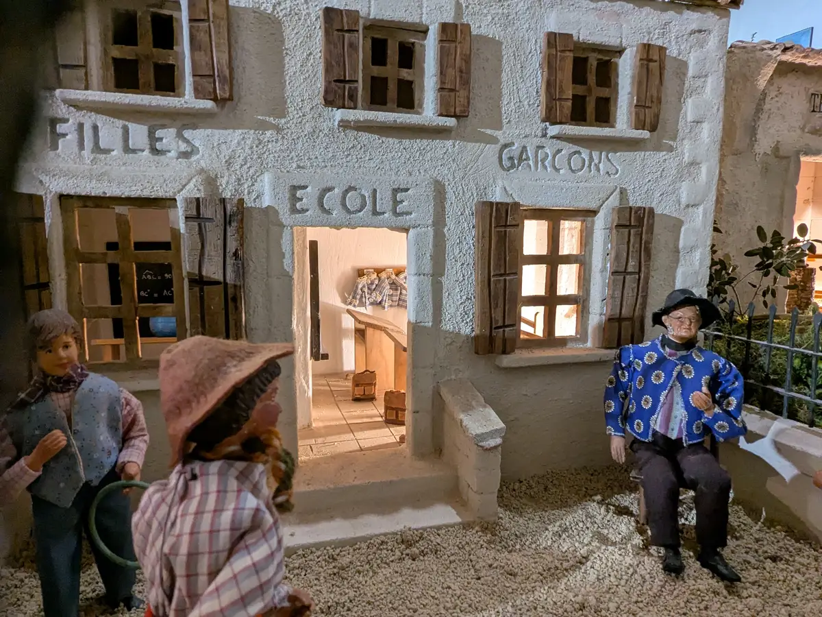 Scuola in miniatura con le scritte Filles e Garçons e santons in primo piano