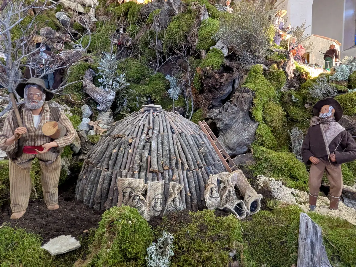 Due santons di carbonai accanto a una catasta di legna e a sacchi nel presepe di Banon
