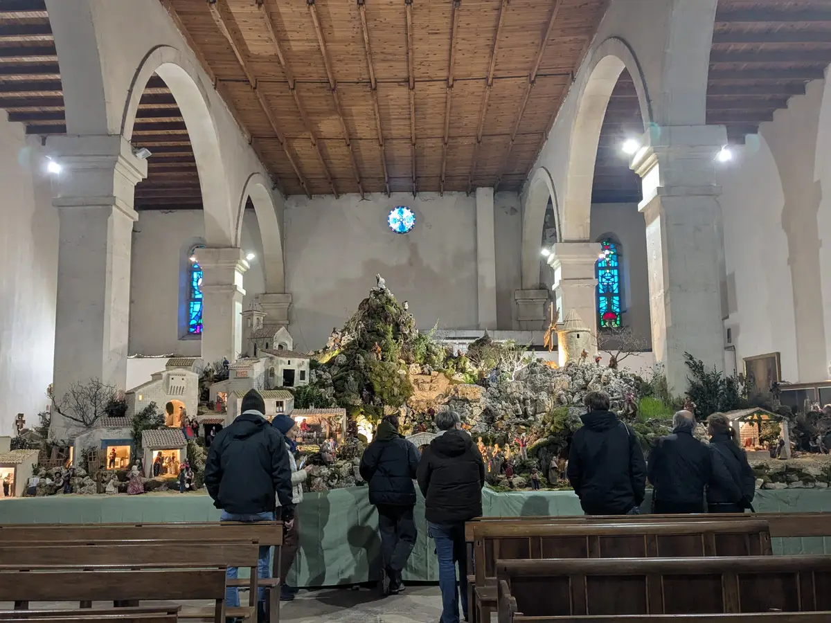 Visitatori davanti all’intero presepe sotto le arcate della chiesa di Notre-Dame-de-l’Assomption a Banon