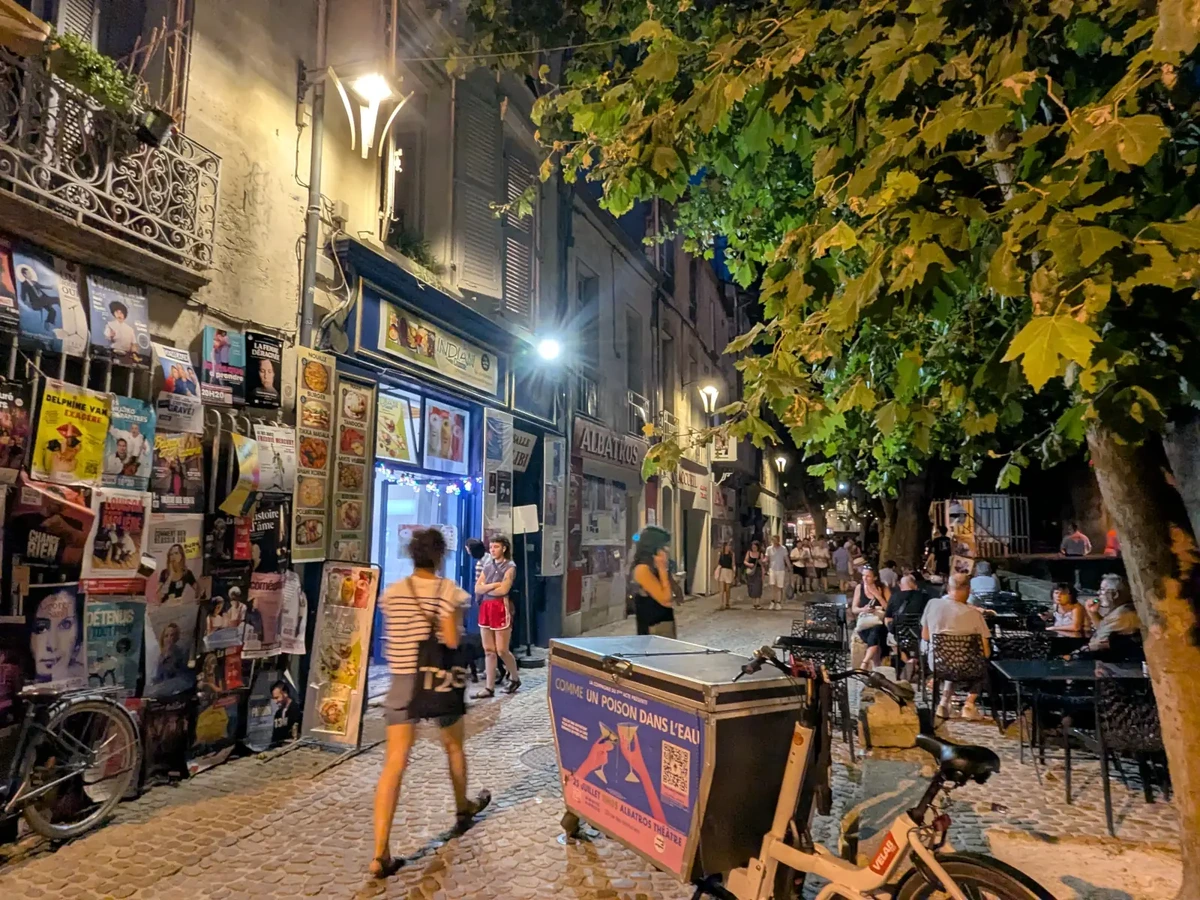 Affiches, théâtre et terrasses de la rue des Teinturiers pendant une soirée de Festival