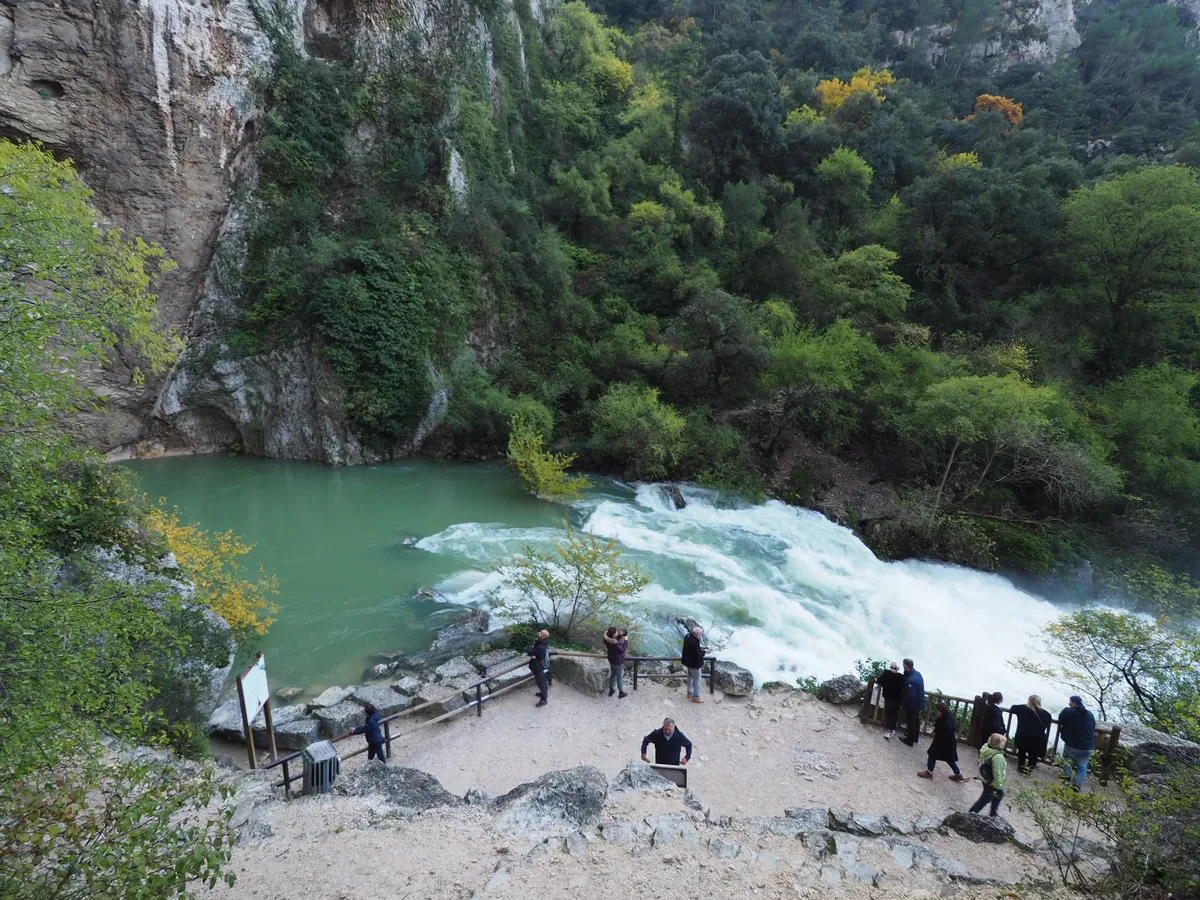 Die Karstquelle der Sorgue bei Hochwasser in Fontaine-de-Vaucluse, am Fuß der Felswand