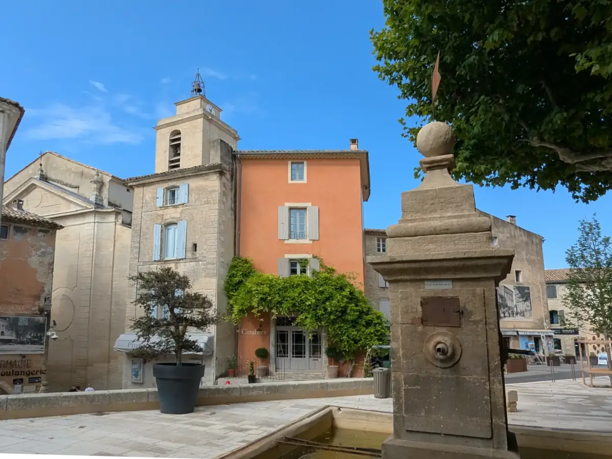 Brunnen auf der Place Genty Pantaly vor den Häusern und dem Glockenturm von Saint-Firmin in Gordes
