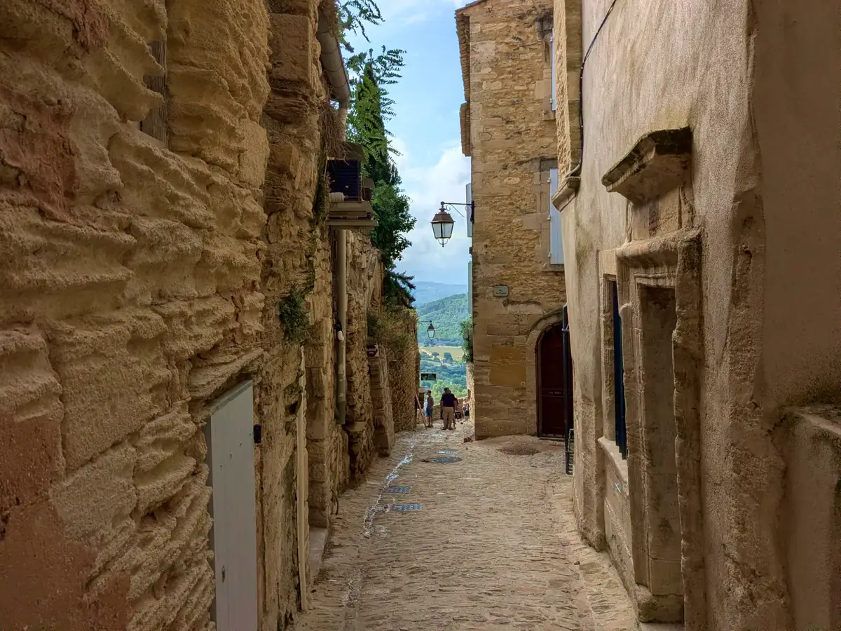 Schmale Gasse, die zwischen den Steinhäusern von Gordes hinabführt