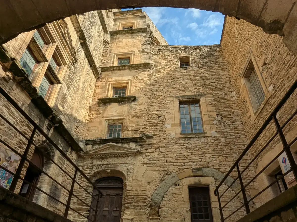 Innenhof des Schlosses von Gordes unter einem steinernen Bogen hindurch gesehen