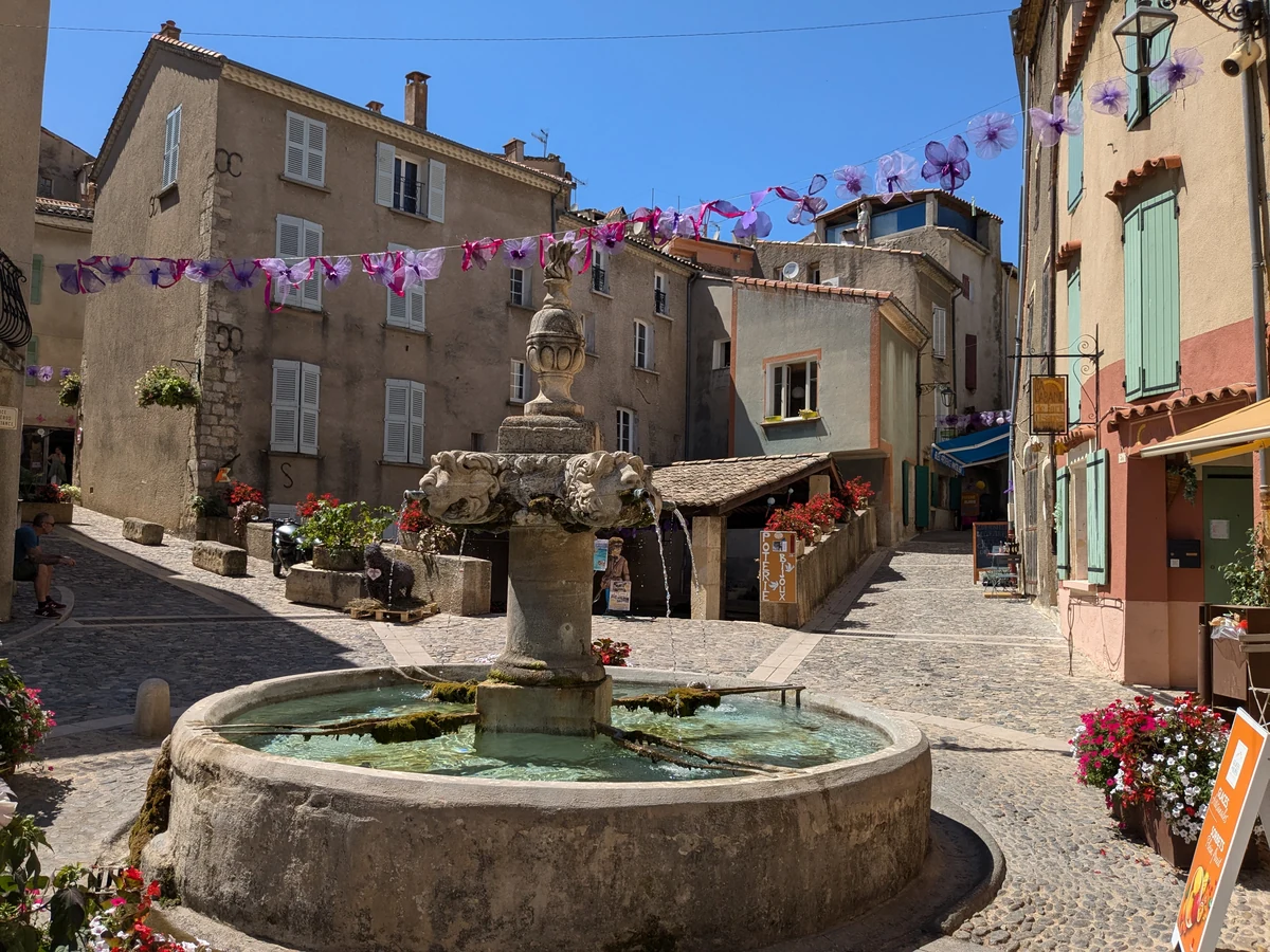 Fontana scolpita e case attorno a una piazza del paese di Valensole