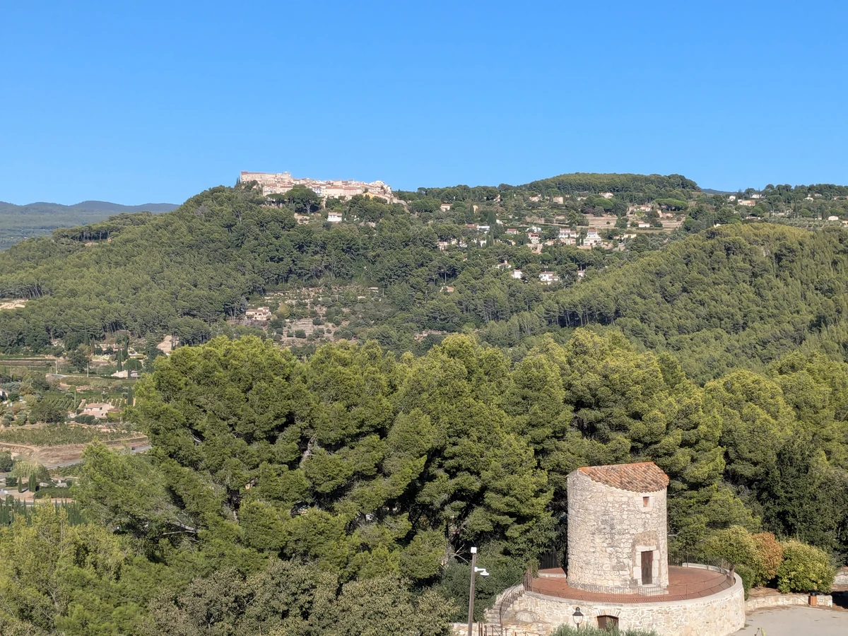 Le Castellet auf seinem Hügel, von La Cadière-d’Azur aus gesehen, mit einer Mühle im Vordergrund