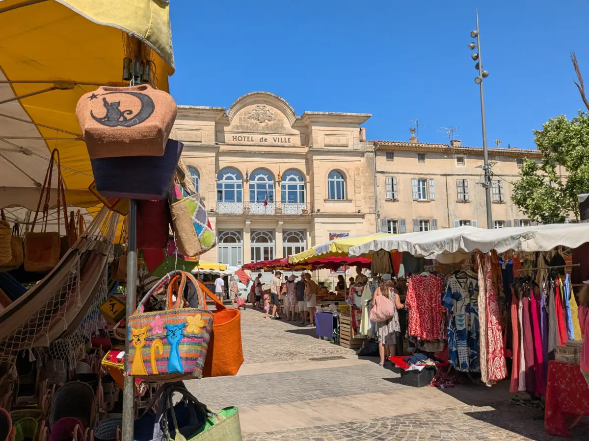 Bags and clothes on market stalls in the square in front of Apt’s town hall