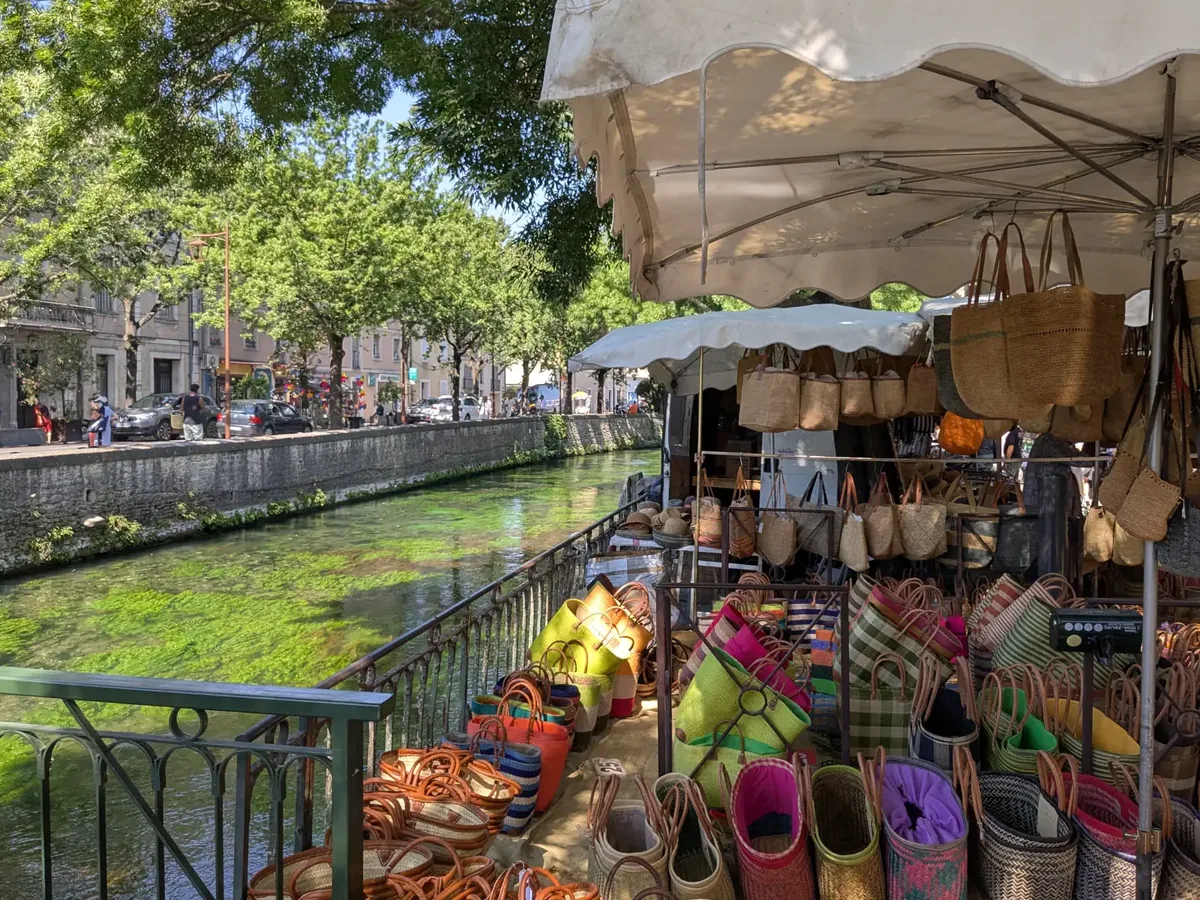 Korbwarenstand an einem Kai von L’Isle-sur-la-Sorgue, im Hintergrund die Sorgue