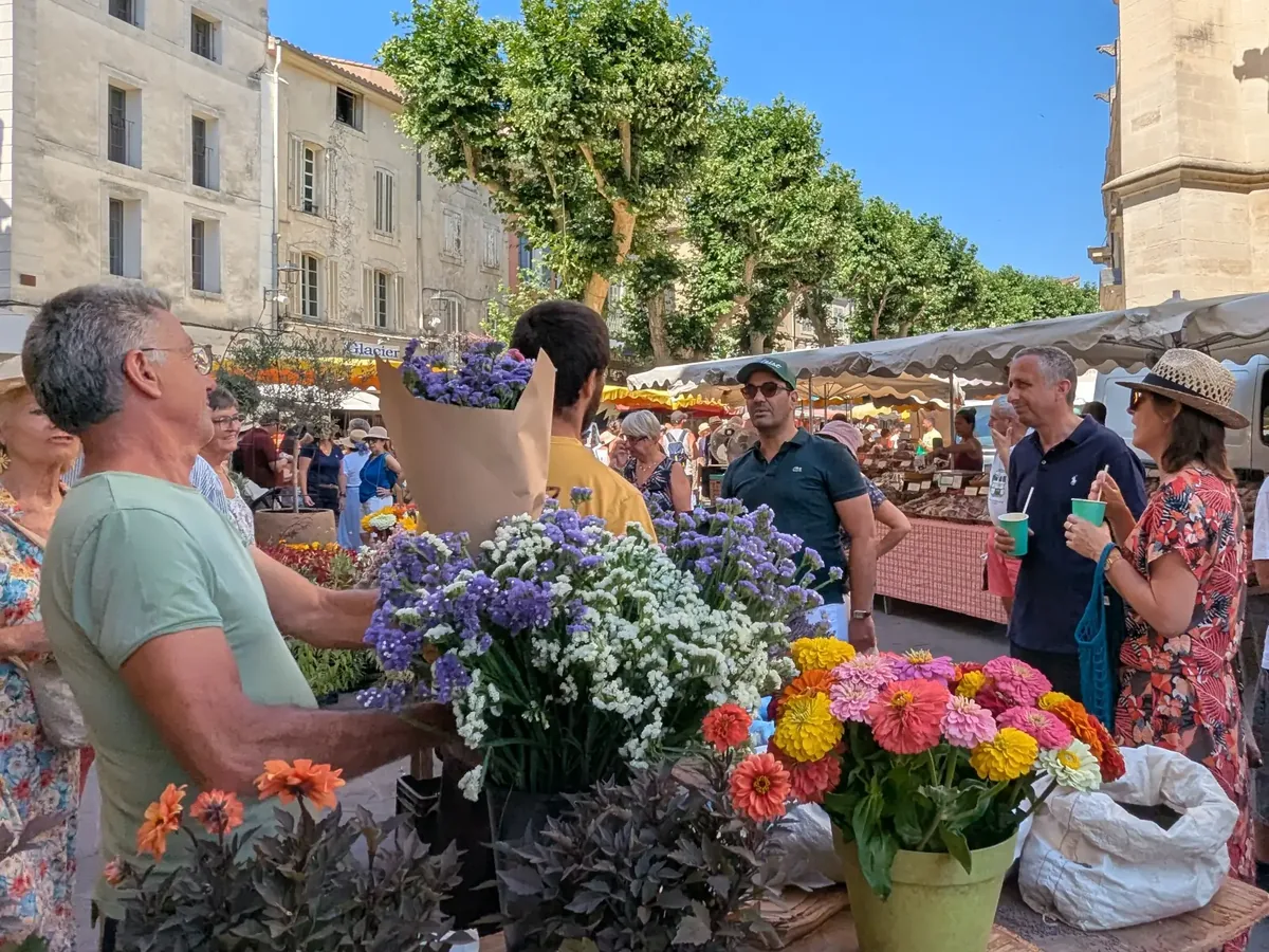 Blumensträuße und Kunden an einem Stand des Marktes von L’Isle-sur-la-Sorgue