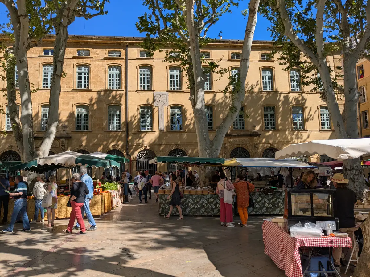 Étals et clients du marché de la place Richelme devant la façade de la halle aux grains à Aix-en-Provence