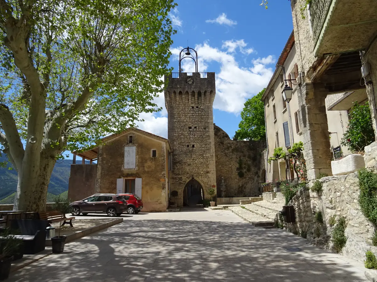 Tour du beffroi et sa porte au fond de la place ombragée de Montbrun-les-Bains