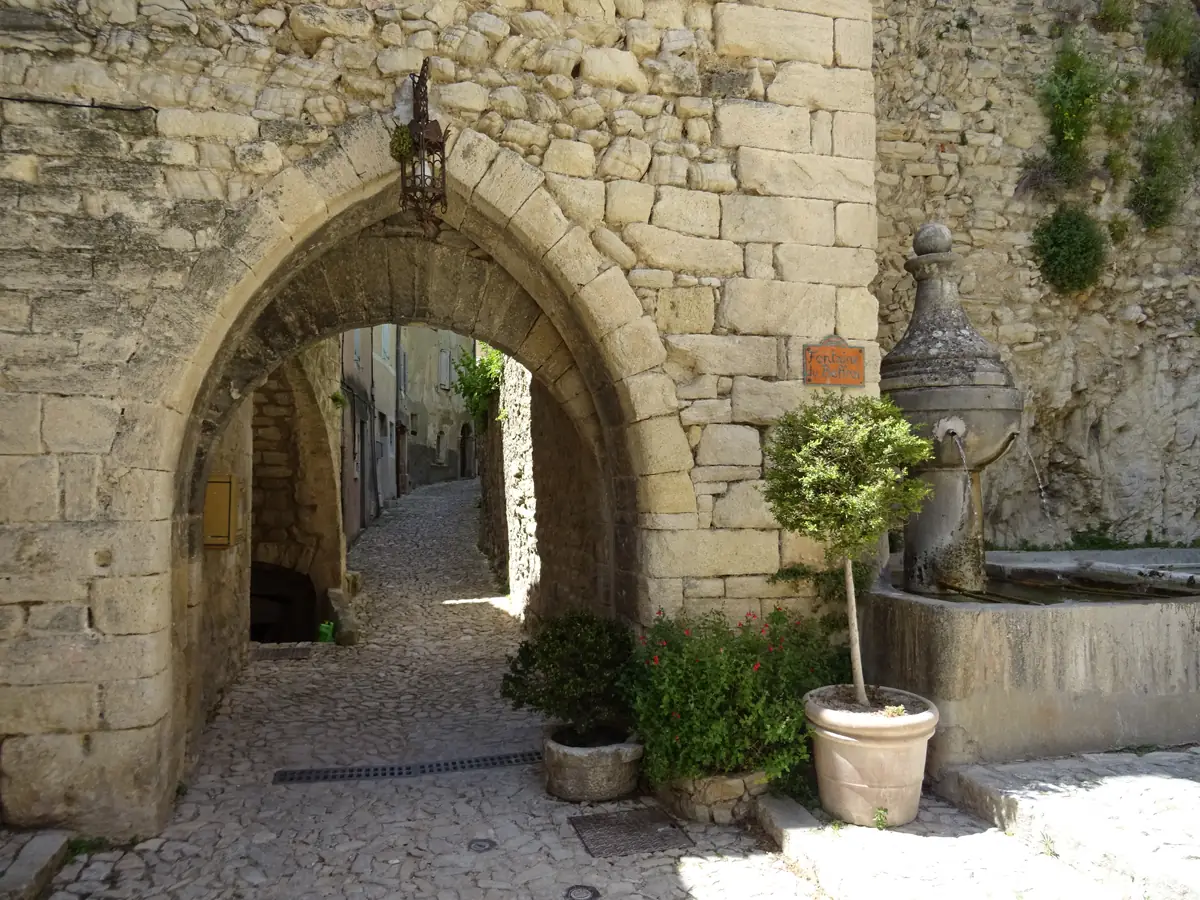 Fontaine à bassin de pierre à côté de la porte en arc brisé du beffroi