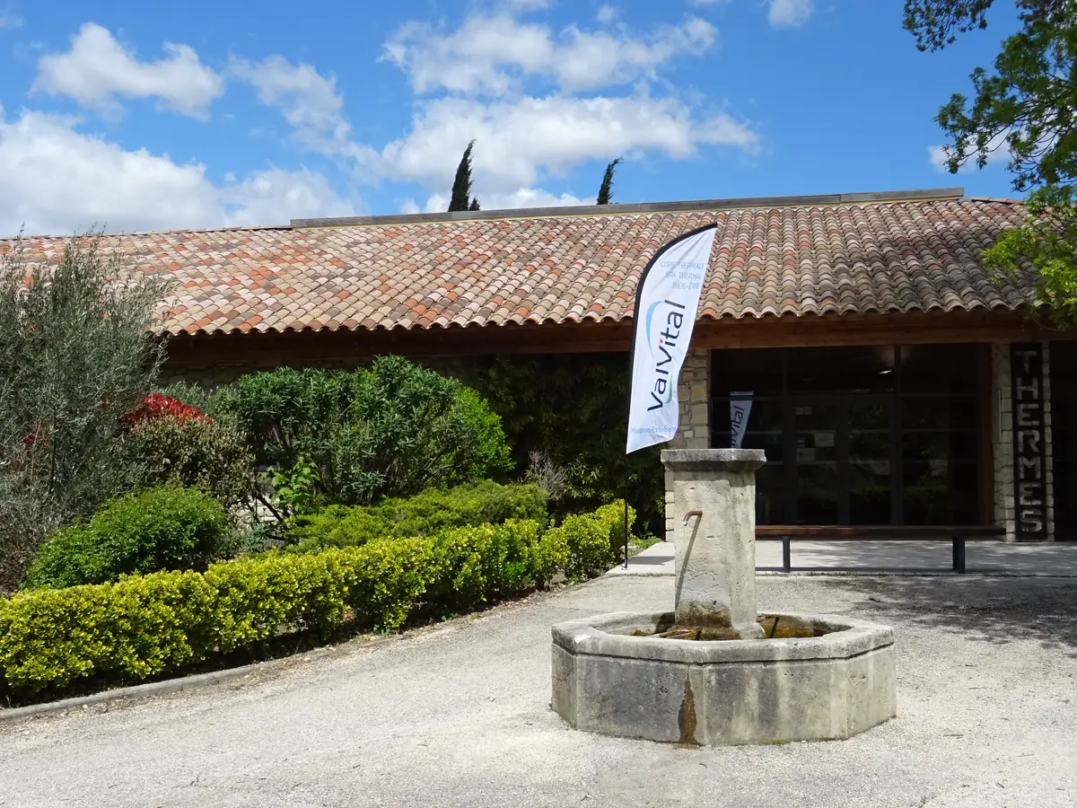 Entrée des thermes contemporains de Montbrun-les-Bains, avec une fontaine et une enseigne Valvital