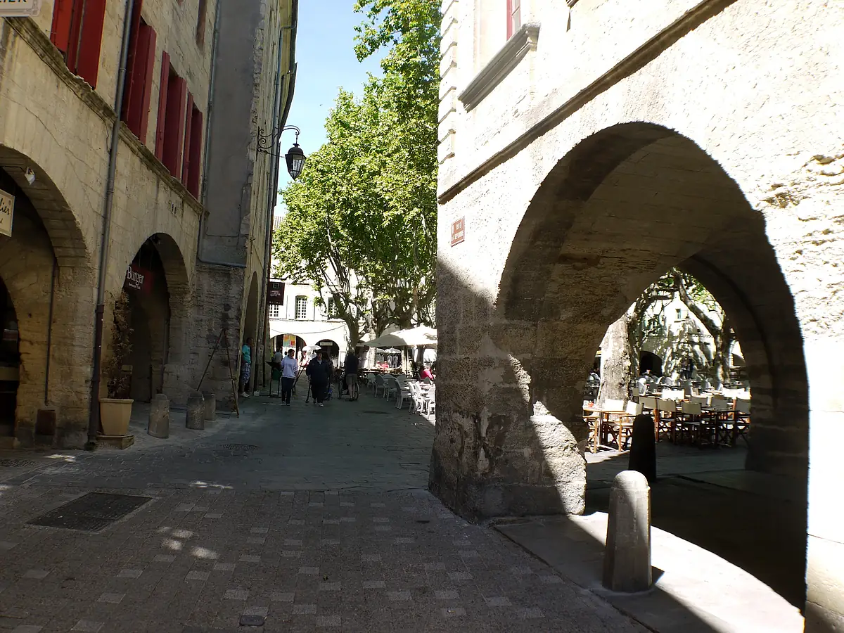 Stone arcade opening onto Place aux Herbes in Uzès