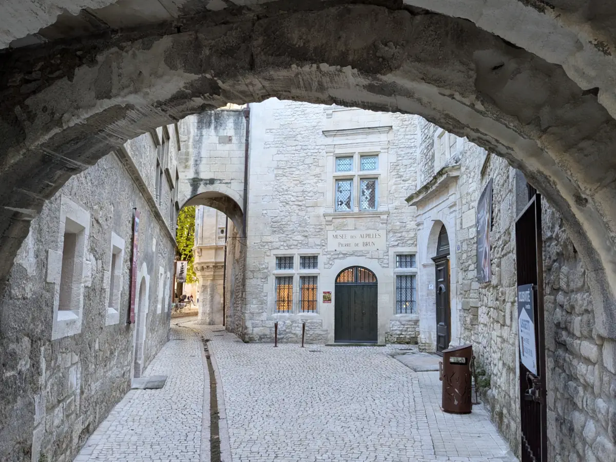 Die rückwärtige Fassade des Musée des Alpilles unter einem Gewölbe der Rue du Parage