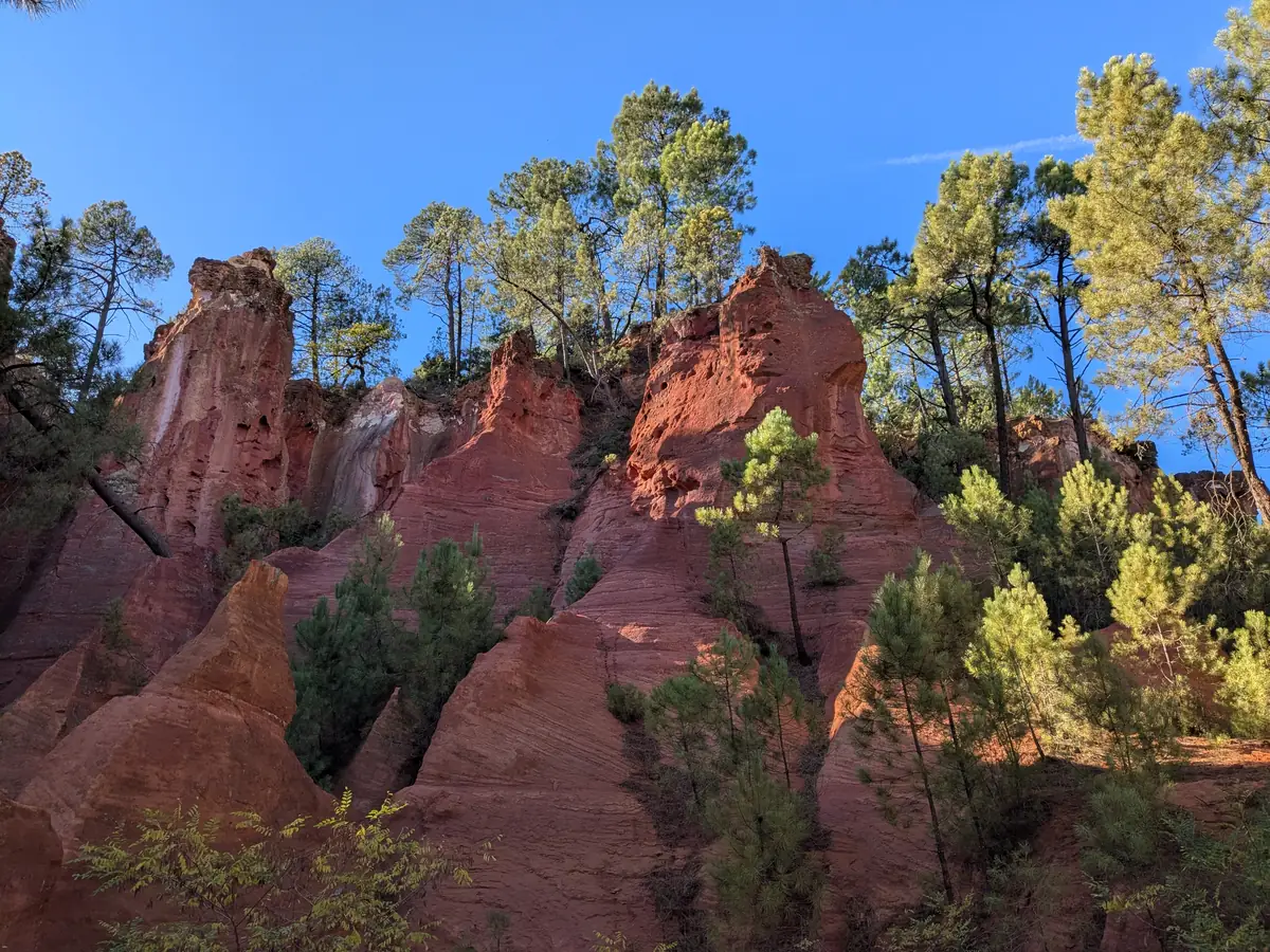 Red cliffs and sand pinnacles surrounded by pines on the Sentier des Ocres in Roussillon