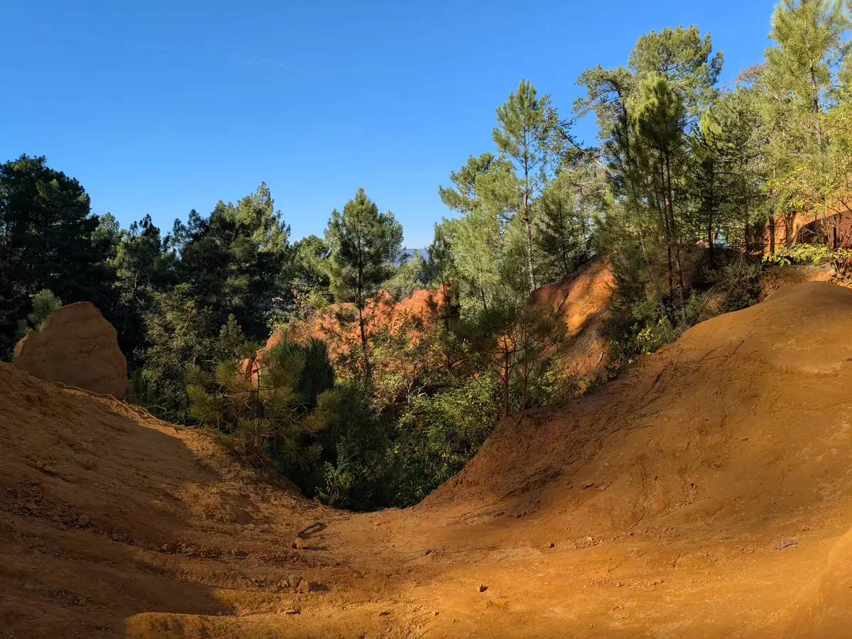 Passage through yellow and orange sands bordered by vegetation in Roussillon