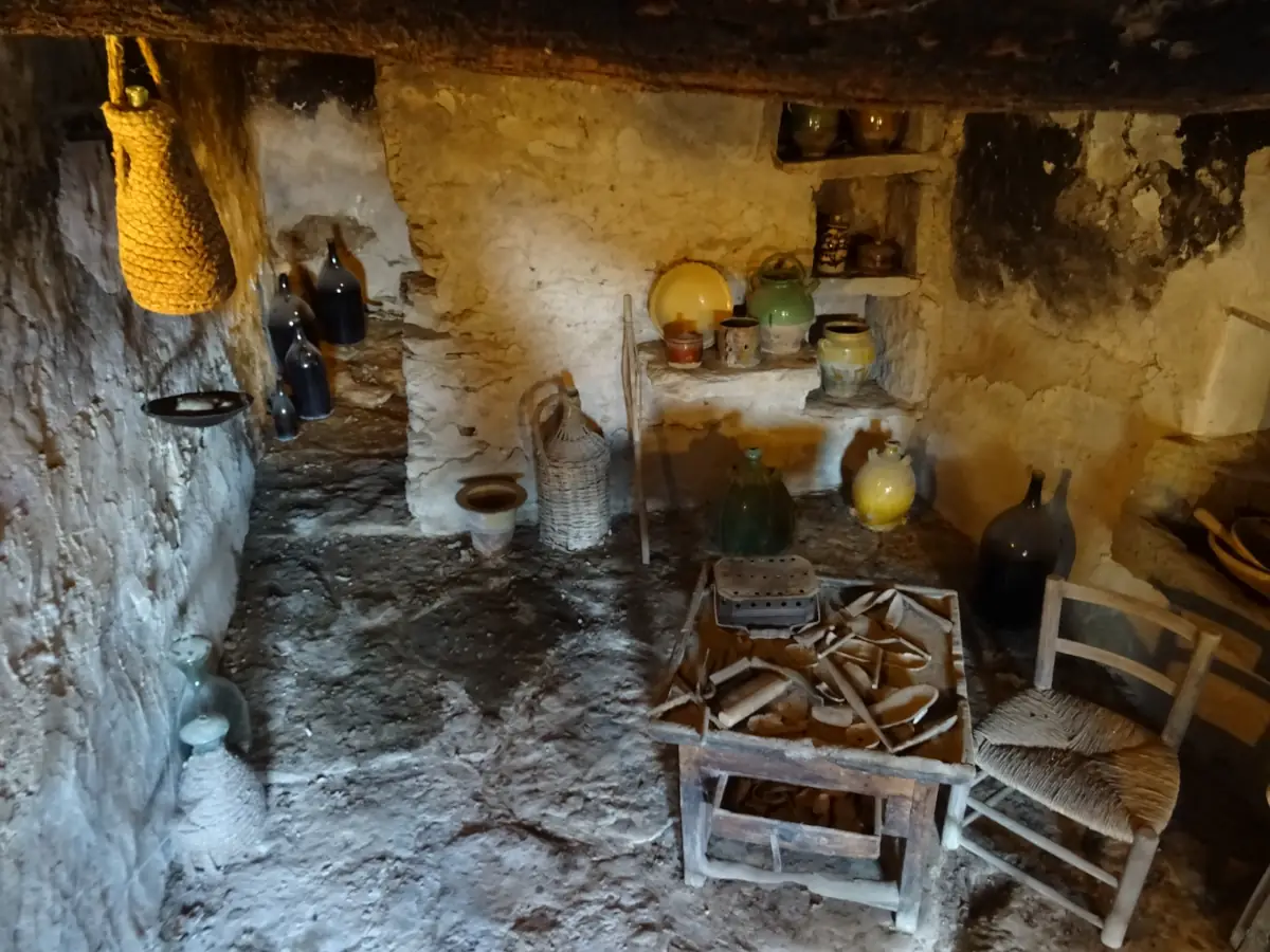 Intérieur aménagé d’une cabane du Village des Bories avec jarres, paniers et outils