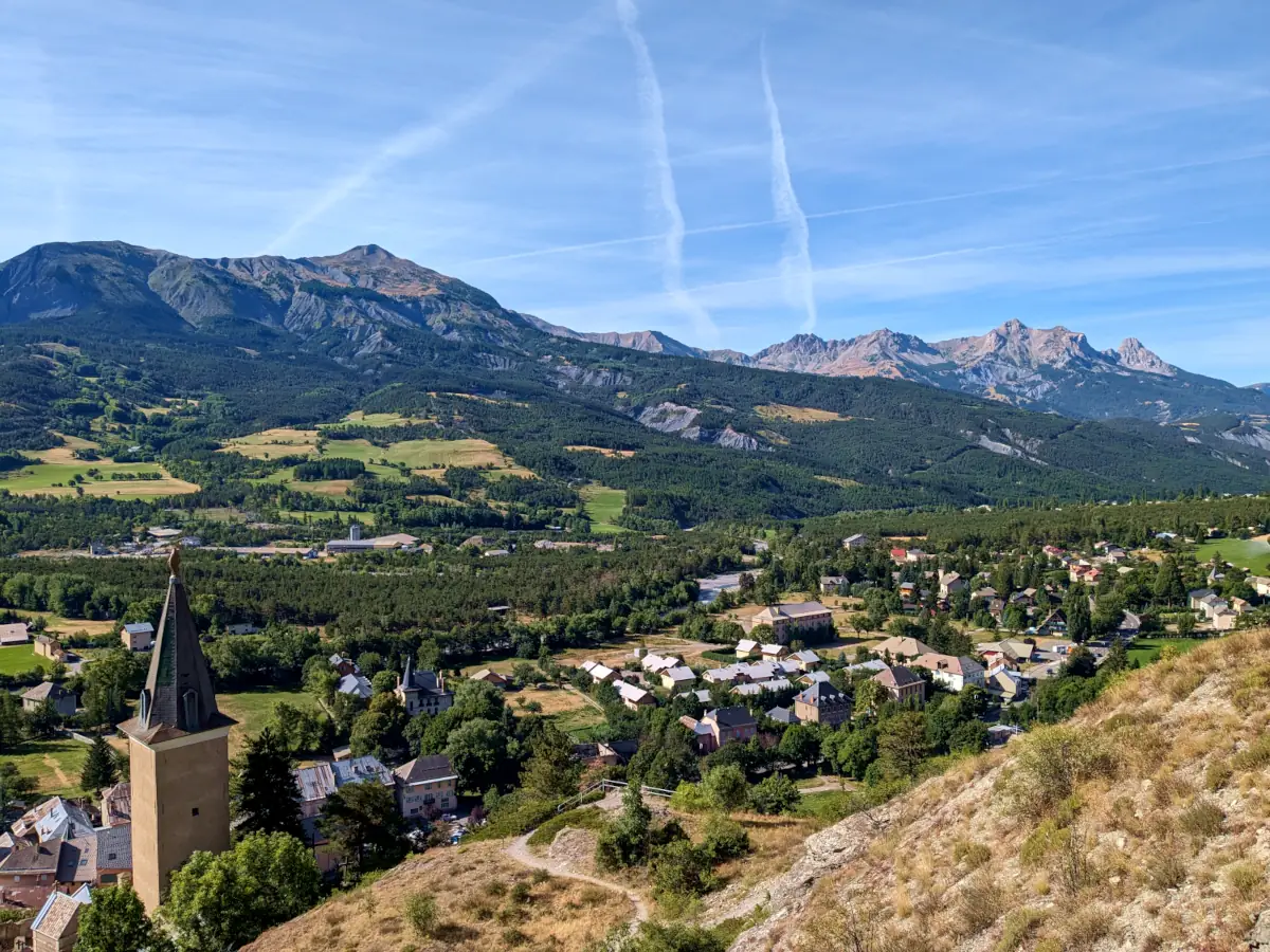 Jausiers and the Ubaye valley seen from the Rocher du Chastel viewpoint, the bell tower of Saint-Nicolas-de-Myre in the foreground